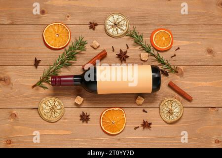 Flasche Wein und verschiedene Gewürze auf hölzernem Hintergrund Stockfoto