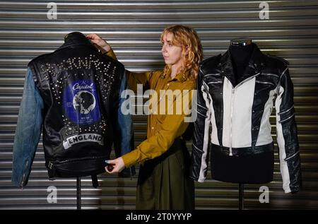 Ein Mitarbeiter von Propstore passt George Michaels Bildschirm an die La Rocka Jacket (links) aus dem Musikvideo zu „I kannte You Were Waiting (for Me)“ (geschätzte £30.000 - 60.000) an, das neben Michael Jacksons maßgefertigter Lederjacke aus einem Pepsi New Generation Werbespot aus dem Jahr 1984 steht (geschätzte £200.000 - 400.000). während einer Vorschau für die Entertainment Memorabilia Auction im Propstore in Rickmansworth, Hertfordshire. Bilddatum: Mittwoch, 20. September 2023. Stockfoto