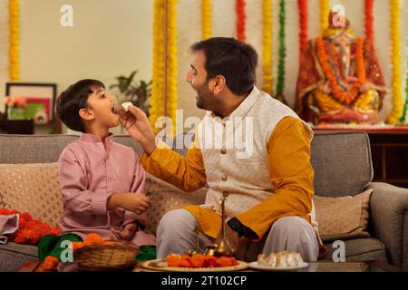 Vater fütterte modak seinem Sohn anlässlich von Ganesh Chaturthi Stockfoto