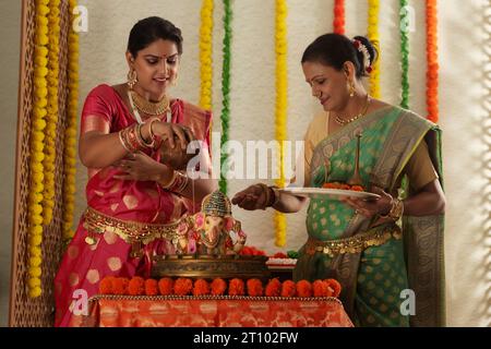Schwiegermutter und Schwiegertochter verehren Lord Ganesha zusammen auf Ganesh Chaturthi Stockfoto