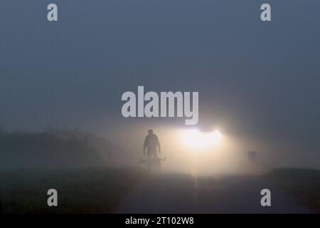 Herbst im Siegerland. Am fruehen frühen Morgen liegt dichter Nebel ueber der Landschaft wie hier in Siegen-Oberschelden. Ein Mann geht mit seinem Hund im Nebel spazieren. Im Hintergrund ein Auto mit Licht. Herbst im Siegerland am 10.10.2023 in Siegen/Deutschland. *** Herbst im Siegerland am frühen Morgen liegt dichter Nebel über der Landschaft wie hier in Siegen Oberschelden geht Ein Mann mit seinem Hund im Nebel im Hintergrund ein Auto mit hellem Herbst im Siegerland am 10 10 10 2023 in Siegen Deutschland Credit: Imago/Alamy Live News Stockfoto