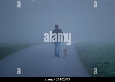 Herbst im Siegerland. Am fruehen frühen Morgen liegt dichter Nebel ueber der Landschaft wie hier in Siegen-Oberschelden. Ein Mann geht mit seinem Hund im Nebel spazieren. Herbst im Siegerland am 10.10.2023 in Siegen/Deutschland. *** Herbst im Siegerland am frühen Morgen liegt dicker Nebel über der Landschaft, da hier in Siegen Oberschelden Ein Mann mit seinem Hund im Nebel spaziert Herbst im Siegerland am 10 10 2023 in Siegen Deutschland Credit: Imago/Alamy Live News Stockfoto