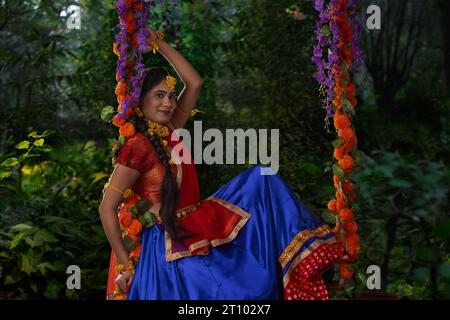 Eine junge Frau, verkleidet als Radha und sitzend auf einer Schaukel anlässlich von Janmashtami Stockfoto