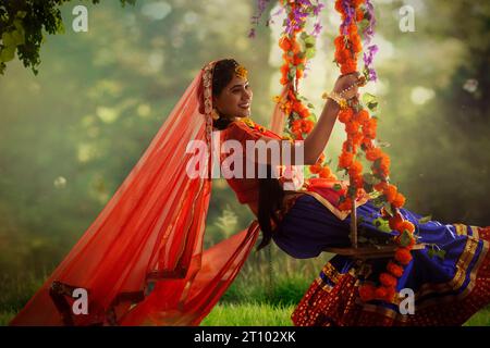 Eine junge Frau, verkleidet als Radha und sitzend auf einer Schaukel anlässlich von Janmashtami Stockfoto