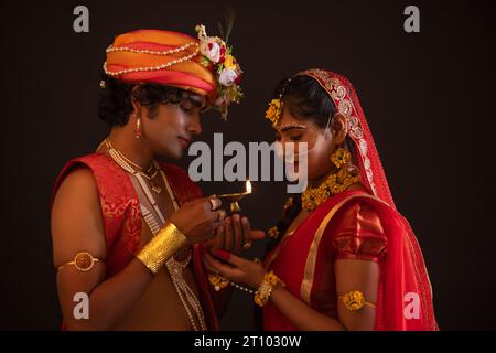 Junger Mann und Frau verkleidet als Lord Radha und Krishna und halten Diya zusammen anlässlich von Janmashtami Stockfoto