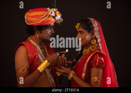 Junger Mann und Frau verkleidet als Lord Radha und Krishna und halten Diya zusammen anlässlich von Janmashtami Stockfoto