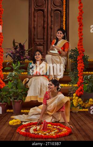 Frauen dekorieren den Boden mit Blumen anlässlich von Onam Stockfoto
