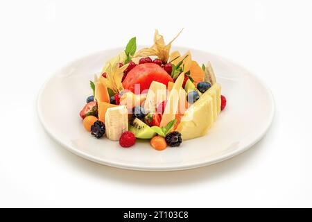 Gemischte Obstsorten auf weißem Porzellanteller auf Holztisch Stockfoto
