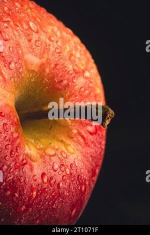 Extreme Nahaufnahme eines Apfels auf schwarzem Hintergrund, mit Spritzern und kleinen Tropfen. Stockfoto
