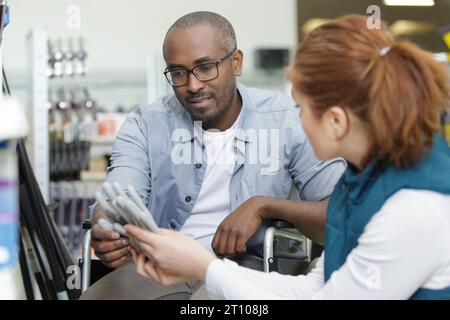 Eine Verkäuferin berät behinderte Männer beim Kauf von Handschuhen Stockfoto