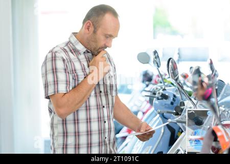 Männlicher Kunde, der im Motorradausstellungsraum stöbert Stockfoto