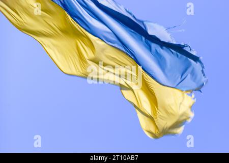 Ukrainische Flagge winkt bei Wind und Sonnenlicht. Flagge der Ukraine auf blauem Himmel Hintergrund. Nationales Symbol für Freiheit und Unabhängigkeit. Stockfoto