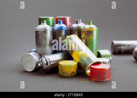 Mehrere farbige Sprühdosen in einem Stapel vor grauem Hintergrund. Eine Kollektion farbenfroher Acrylfarbe in Aerosol, perfekt für kreative Projekte Stockfoto