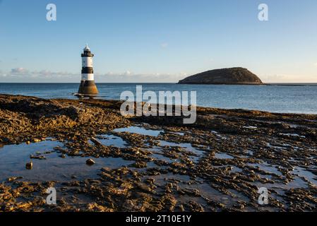 Penmon Point an der Küste von Anglesey, Nordwales. Trwyn du Lighthouse mit Puffin Island dahinter. Stockfoto