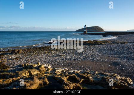 Penmon Point an der Küste von Anglesey, Nordwales. Trwyn du Lighthouse mit Puffin Island dahinter. Stockfoto