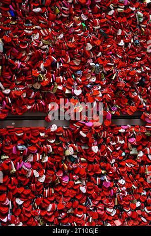 Rote herzförmige Vorhängeschlösser an einer Wand Stockfoto