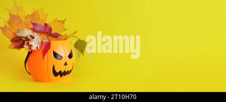 Frohes Halloween. Plastikkübel mit einem bösen Lächeln auf gelbem Hintergrund, leerer Platz für Text. Kopierbereich. Banner für Halloween. Ein Blumenstrauß o Stockfoto