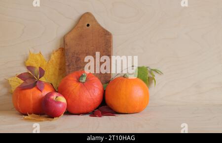 Reife Kürbisse, Äpfel und Herbstblätter auf hölzernem Hintergrund, Seitenansicht. Konzept der Herbsternte. Fotos für saisonale Banner. Produkte auf dem Tisch. Stockfoto