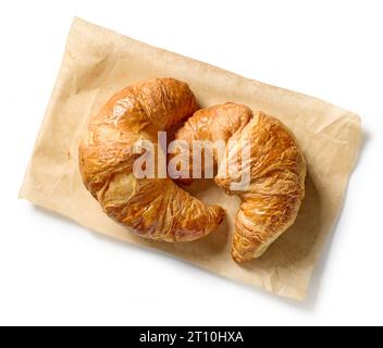 Frisch gebackene Croissants auf Backpapier isoliert auf weißem Hintergrund, Draufsicht Stockfoto