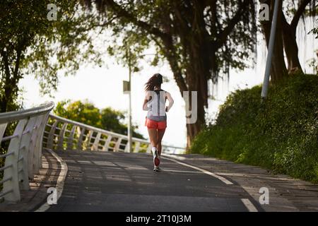 Rückansicht einer jungen asiatischen Joggerin, die im Stadtpark im Freien trainiert Stockfoto