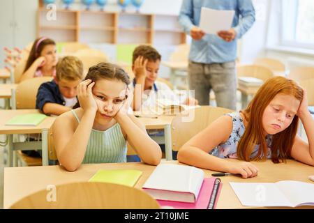 Müde Freundinnen sitzen während des Vortrags im Klassenzimmer auf der Bank Stockfoto