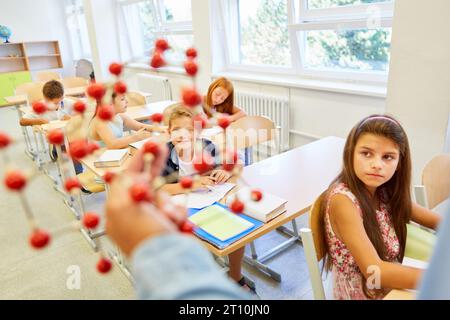 Männliche und weibliche Schulkinder studieren durch molekulare Struktur während der Vorlesung im Klassenzimmer Stockfoto