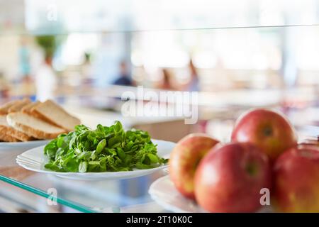 Salatblätter mit Äpfeln und Brot auf Tellern in der Schulkantine Stockfoto