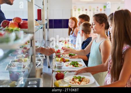 Gruppe von Kindern als Grundschüler am Buffet, genießen eine Vielfalt an Speisen Stockfoto