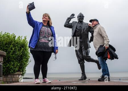 Touristen fotografieren die Statue von Eric Morecambe an der Küste von Morecambe, Lancashire Stockfoto