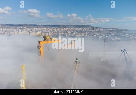 Luftaufnahme von Kranen in Hafenindustriezone bei Morgennebel Stockfoto