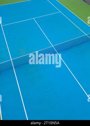 Aus der Vogelperspektive auf einen ruhigen blau-grünen Tennisplatz in einem leeren Zustand, der die gut gepflegte Oberfläche des Platzes und die Linien, die ihn markieren, hervorhebt Stockfoto