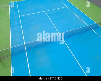 Aus der Vogelperspektive auf einen ruhigen blau-grünen Tennisplatz in einem leeren Zustand, der die gut gepflegte Oberfläche des Platzes und die Linien, die ihn markieren, hervorhebt Stockfoto