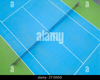 Aus der Vogelperspektive auf einen ruhigen blau-grünen Tennisplatz in einem leeren Zustand, der die gut gepflegte Oberfläche des Platzes und die Linien, die ihn markieren, hervorhebt Stockfoto
