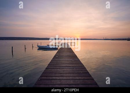 Landschaftsfoto von einem Holzsteg und zwei Booten auf dem See bei Sonnenuntergang in Varna, Bulgarien. Stockfoto