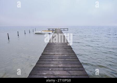 Holzsteg oder Pier am See in nebeliger Stimmung. Stockfoto