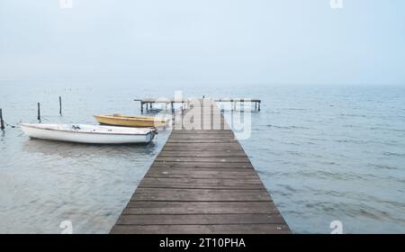 Holzsteg oder Pier am See in nebeliger Stimmung. Stockfoto