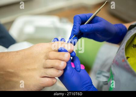 Das Konzept der männlichen Pediküre, der Fußpediküre, der Kosmetiker macht die klassische Pediküre für einen älteren männlichen Klienten. Stockfoto