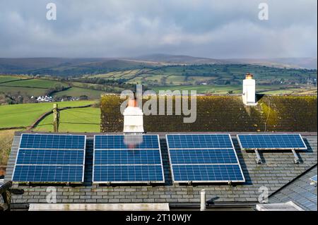 Sonnenkollektoren auf einem Hausdach mit einem wunderschönen Blick auf die Landschaft dahinter. Saubere erneuerbare Energien ohne CO2-Emissionen. Stromerzeugung Stockfoto