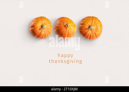 Thanksgiving-Karte: Drei Kürbisse auf Papier mit dem Text "Happy Thanksgiving" unten. Stockfoto