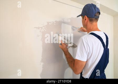 Professioneller Hausmaler, der Löcher und Risse mit Putz repariert. Stockfoto