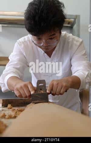 (231010) -- KAIFENG, 10. Oktober 2023 (Xinhua) -- Guqin-Hersteller Xu Bing produziert Guqin im Landkreis Lankao der Stadt Kaifeng, Zentralchinas Provinz Henan, 9. Oktober 2023. Lankao County ist reich an Paulownia-Bäumen, ein idealer Rohstoff für die Herstellung von Musikinstrumenten. Doch im letzten Jahrhundert führten häufige Überschwemmungen und Sandstürme zu schlechten Böden und Ernteausfällen. In den 60er Jahren initiierte der lokale Parteichef Jiao Yulu die Einheimischen, Paulownia-Bäume zu Pflanzen, um den Boden zu verbessern und Wasser zu sparen. In den 1980er Jahren, als die Bäume blühten, fanden die Einheimischen auch das feine Material, um Möbel herzustellen Stockfoto