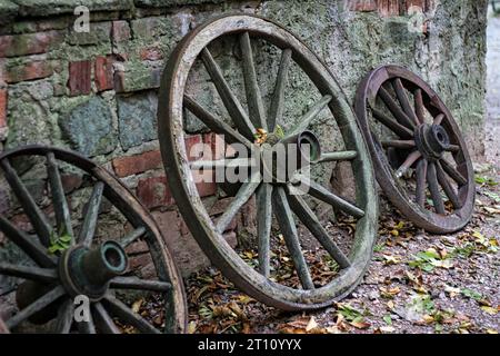 Alte Holzräder stehen an einer Wand. Stockfoto