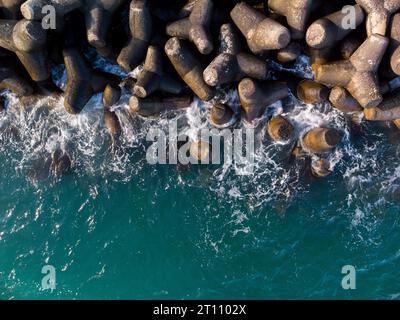 Luftaufnahme der Drone von oben auf einen Wellenbrecher. Wellenbrecher im Meer, eine Ansammlung von Betonbrechern Stockfoto