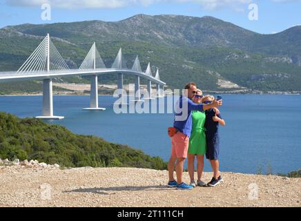 (231010) -- PEKING, 10. Oktober 2023 (Xinhua) -- Menschen machen Selfies vor der Peljesac-Brücke in Komarna, Kroatien, 29. August 2023. Die Brücke, ein Projekt der chinesischen Belt and Road Initiative (BRI), wurde am 26. Juli letzten Jahres für den Verkehr eröffnet. (Xinhua/Li Xuejun) Stockfoto