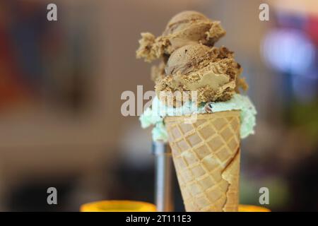 Eiswaffelkegel. Hausgemachtes Eis im Metallhalter. Minz- und Nougateis. Karamell-Phistachios-Eis. Kopierbereich. Selektiver Fokus. Stockfoto