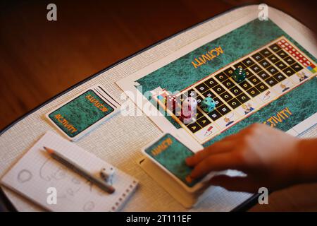 Brunswick, Deutschland - 25. September 2022: Spielfeld des berühmten Brettspiels Activity. Die Hand des Spielers nimmt die Karte. Selektiver Fokus auf die di Stockfoto