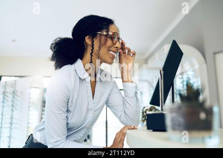 Optometrie, Brille und Frau mit Spiegel für Entscheidung, Wahl und Optionen im Optikerladen für Sehvermögen. Gesundheit, Augenheilkunde und glücklicher Mensch Stockfoto