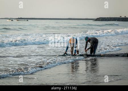 Fischer am frühen Morgen im Dienst am Fujairah Beach, Vereinigte Arabische Emirate. Stockfoto