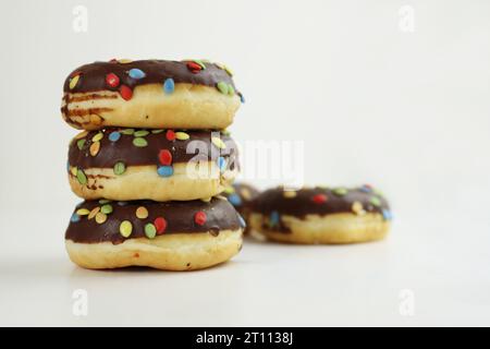 Ein Haufen Donuts, glasiert mit Schokolade und bunten Muscheln. Ein Stapel 5 Donuts, isoliert auf weißem Hintergrund. Seitenansicht. Speicherplatz kopieren Stockfoto