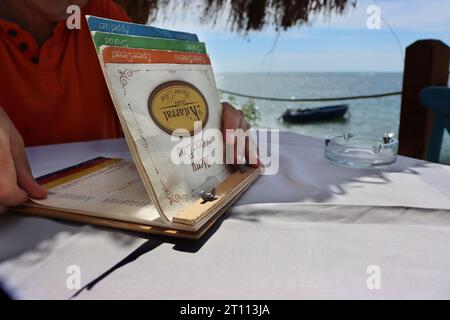 Dürres, Albanien - 3. September 2022: Restaurant 2 Kitarrat AROME Deti. Mann, der die Karte hält und liest, die Mahlzeit auswählt. Wunderschönes Restaurant Stockfoto